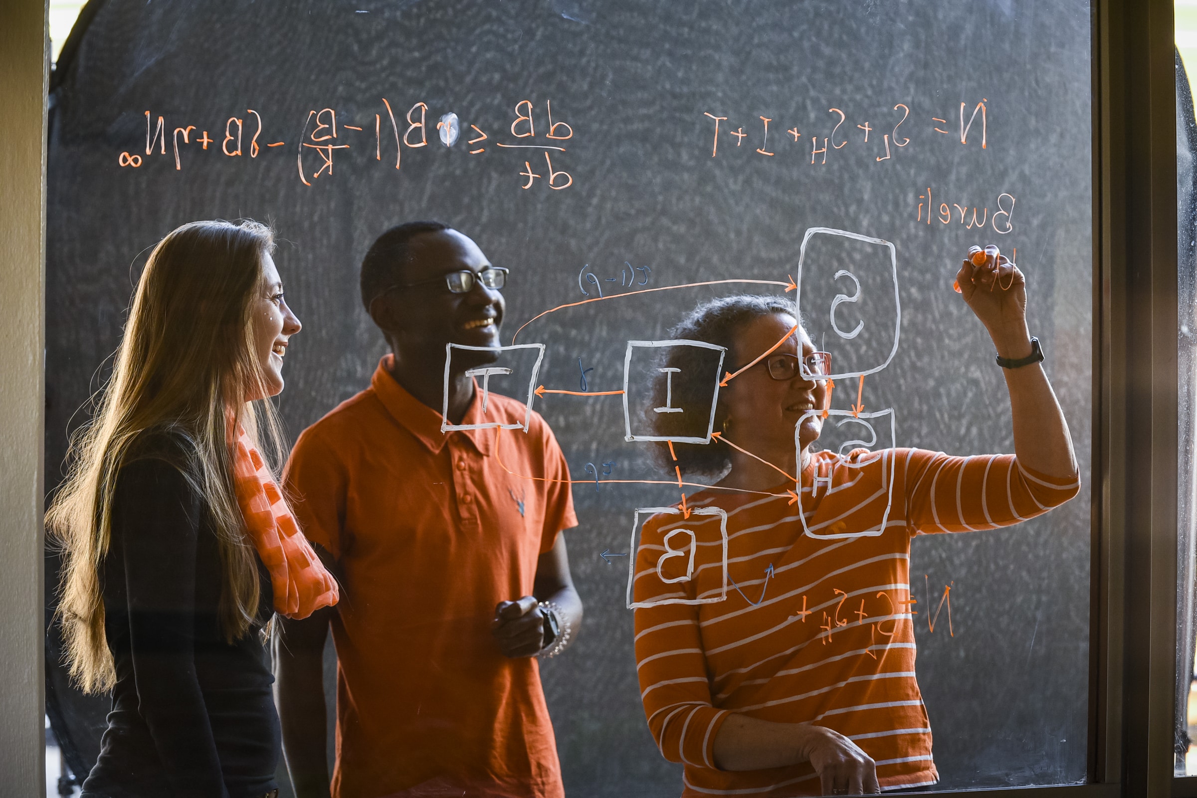UT Professor working with 2 students at a whiteboard