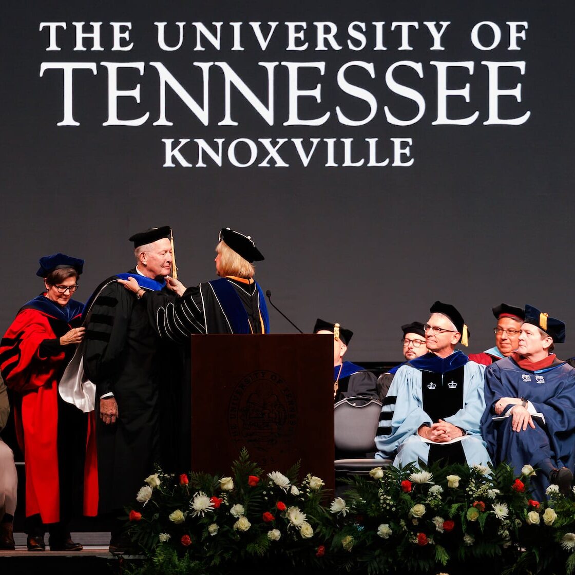 Donde Plowman, Chancellor of the University of Tennessee, helps hood Senator Lamar Alexander, with Ellen McIntyre, Dean of the College of Education, Health and Human Sciences, as Randy Boyd, UT System President, stands by to assist during the Fall Undergraduate Commencement ceremony inside Thompson-Boling Arena at Food City Center