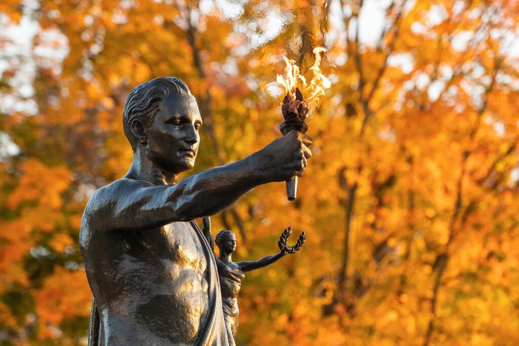 Closeup of the Torchbearer statue with fall foliage in the background